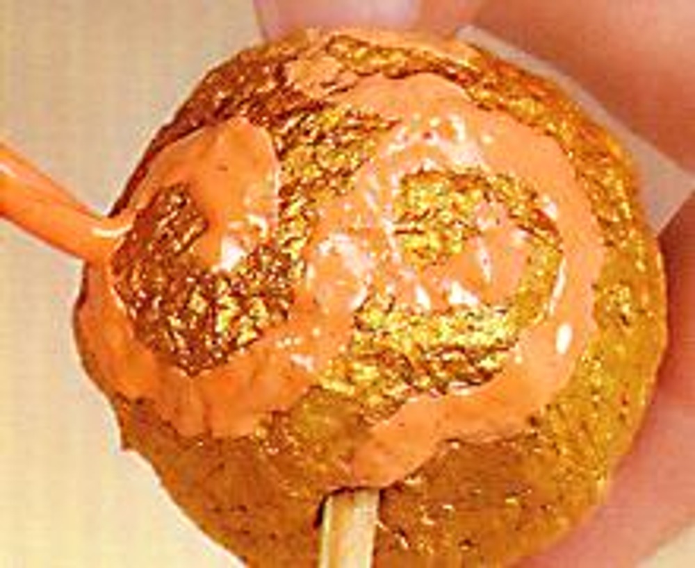 2. Высушите шарики, не снимая их со стержня. После покрасьте бусины золотой краской. Когда золотой слой высохнет, нарисуйте желтой и персиковой краской завитки произвольной формы.