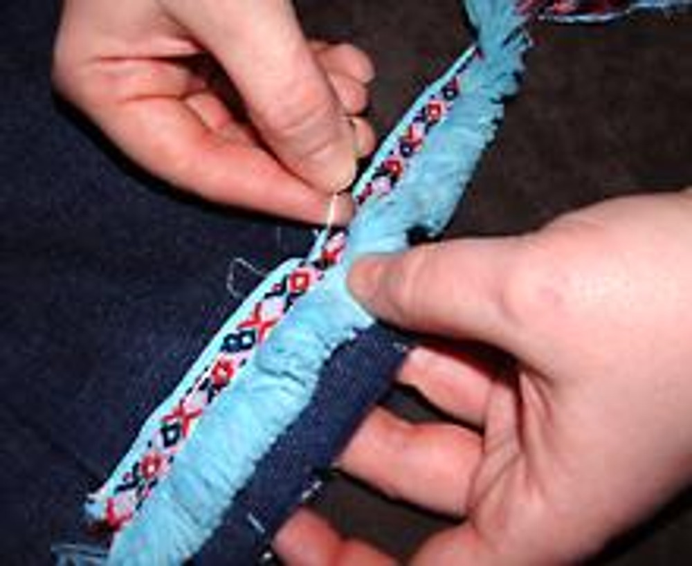 4. Оберните тесьмой каждую штанину на одном и том же уровне. Концы тесьмы заправьте в распоротый шов и зафиксируйте тесьму булавками.