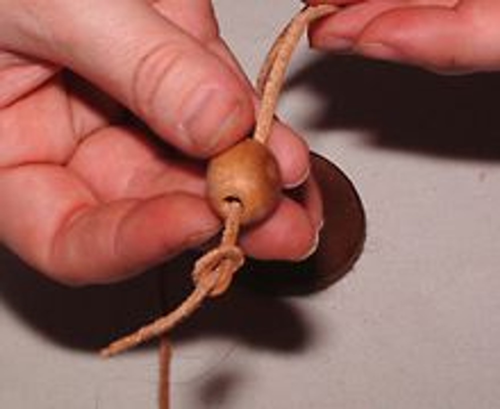 3. На концы шнура наденьте деревянные шарики и завяжите ограничительные узелки, чтобы шарики не соскочили со своего места.