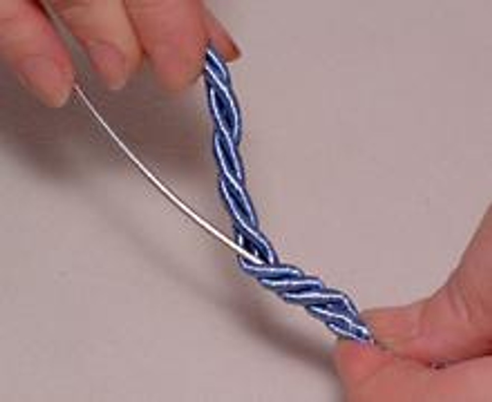 4. Расплетая шнур, вставьте в него ручку из проволоки, одновременно заплетая его обратно пальцами.