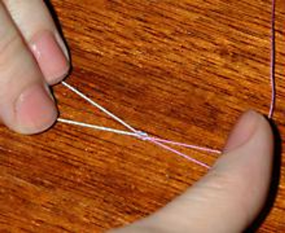 2. Растягиваем пальцами нити в разный стороны, затягивая узелок.